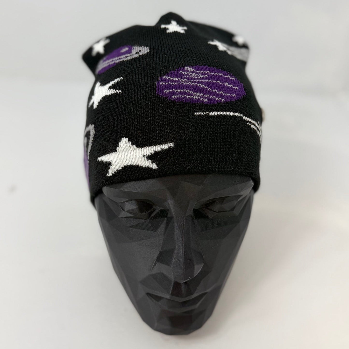 Black beanie with star and planet patterns on a mannequin head against a white background