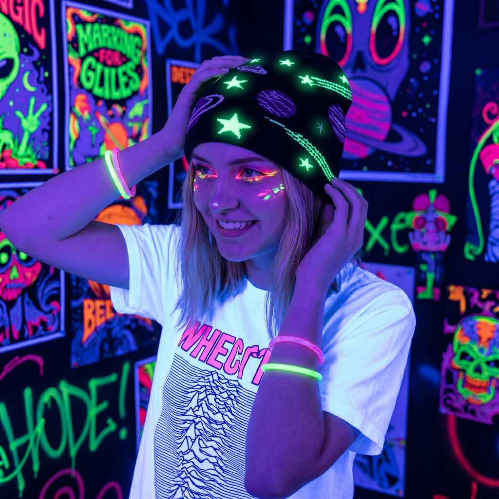 Person wearing a UV-reactive hat and clothing in a neon-lit room with glowing posters.