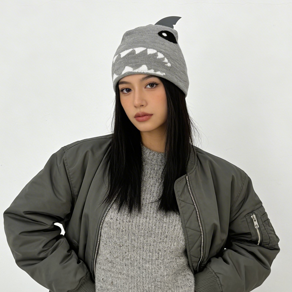 Woman wearing a gray dress, jacket, and shark hat against a white background