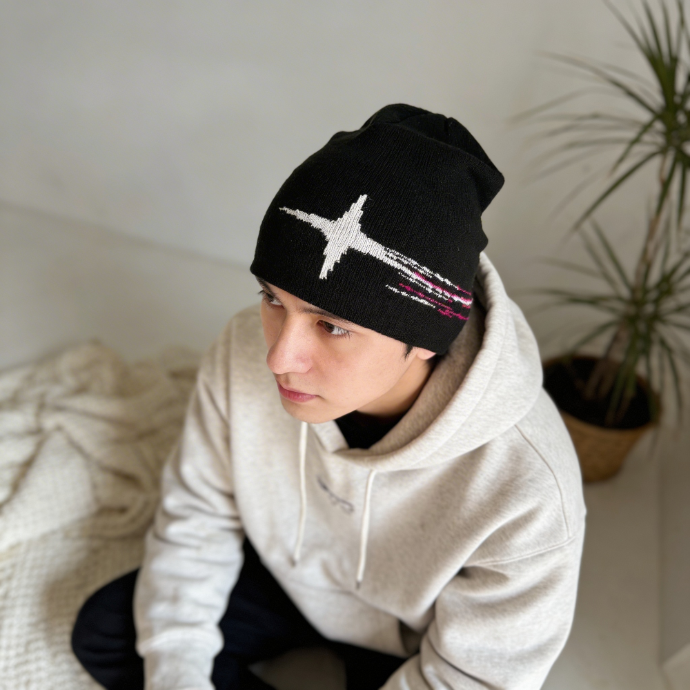 Person wearing a black beanie with a white airplane design indoors.