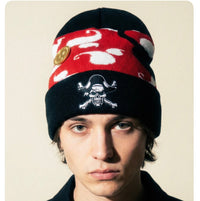 Person wearing a red and black beanie with a skull design on a beige background