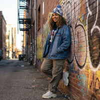 Person leaning against a graffiti-covered wall in an alleyway
