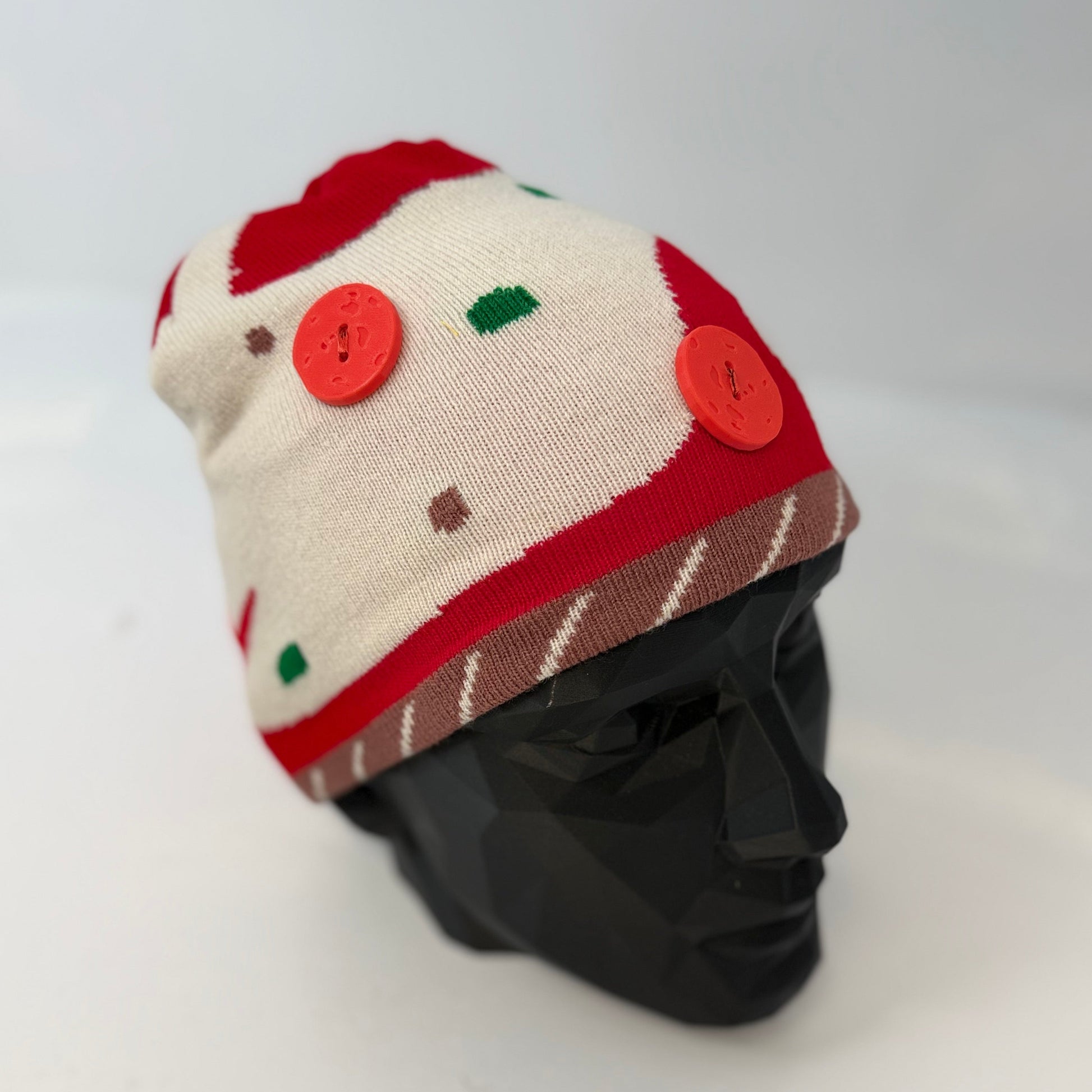 Knitted hat with red and white pattern on a mannequin head against a white background