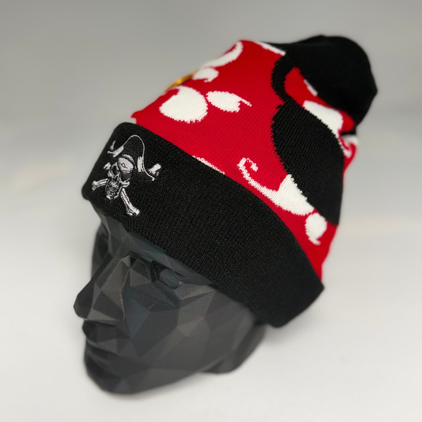 Black and red beanie with skull and crossbones design on a gray mannequin head.