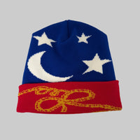 Knitted beanie with blue top, red band, white stars, and yellow design on a white background