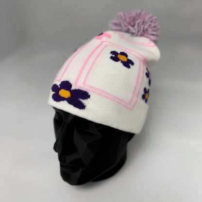 White knit beanie with purple flowers and a pink border on a mannequin head against a white background.