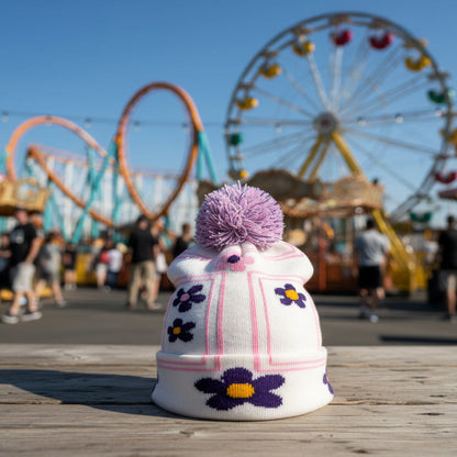 Knitted hat with purple flowers and a pink pom-pom on a white background