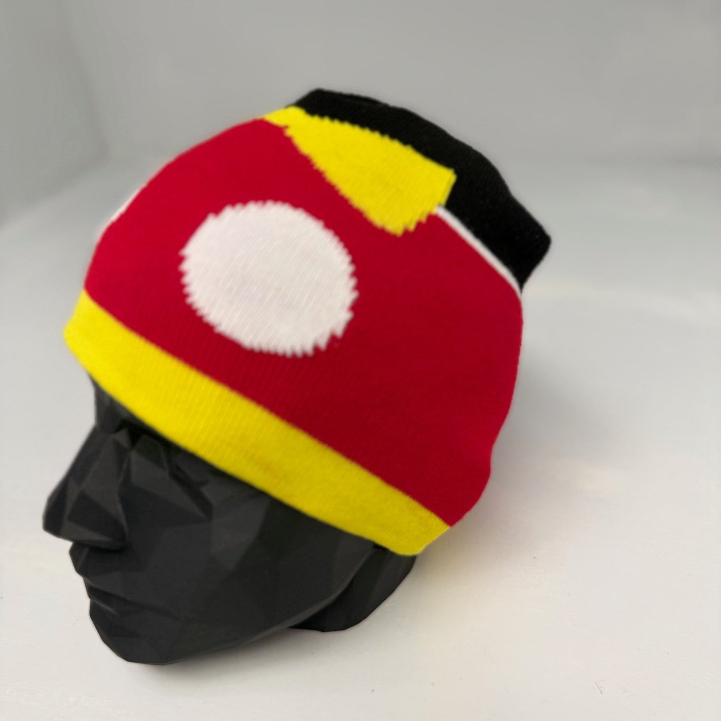 Colorful beanie with red, yellow, and black design on a mannequin head against a white background