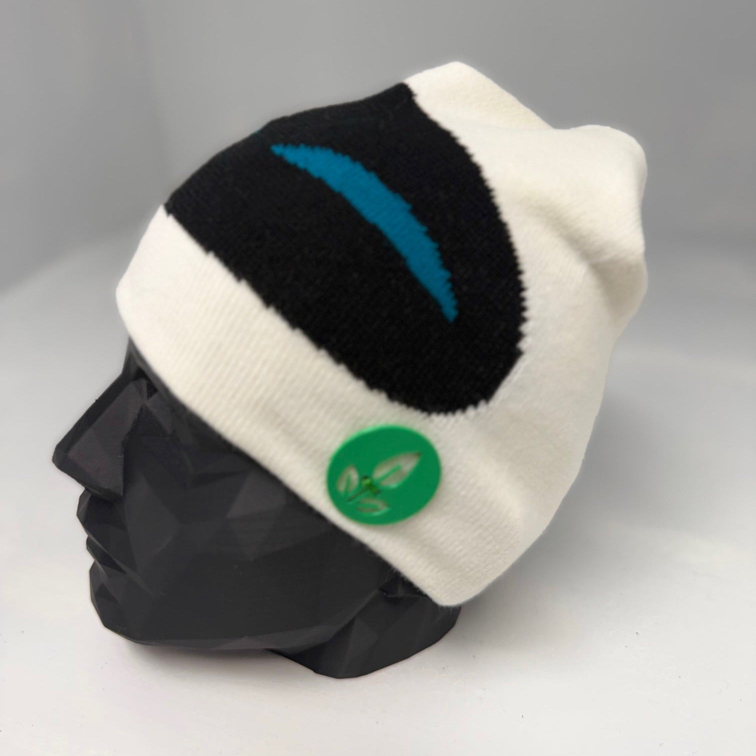 White and black beanie with a green logo on a mannequin head against a gray background
