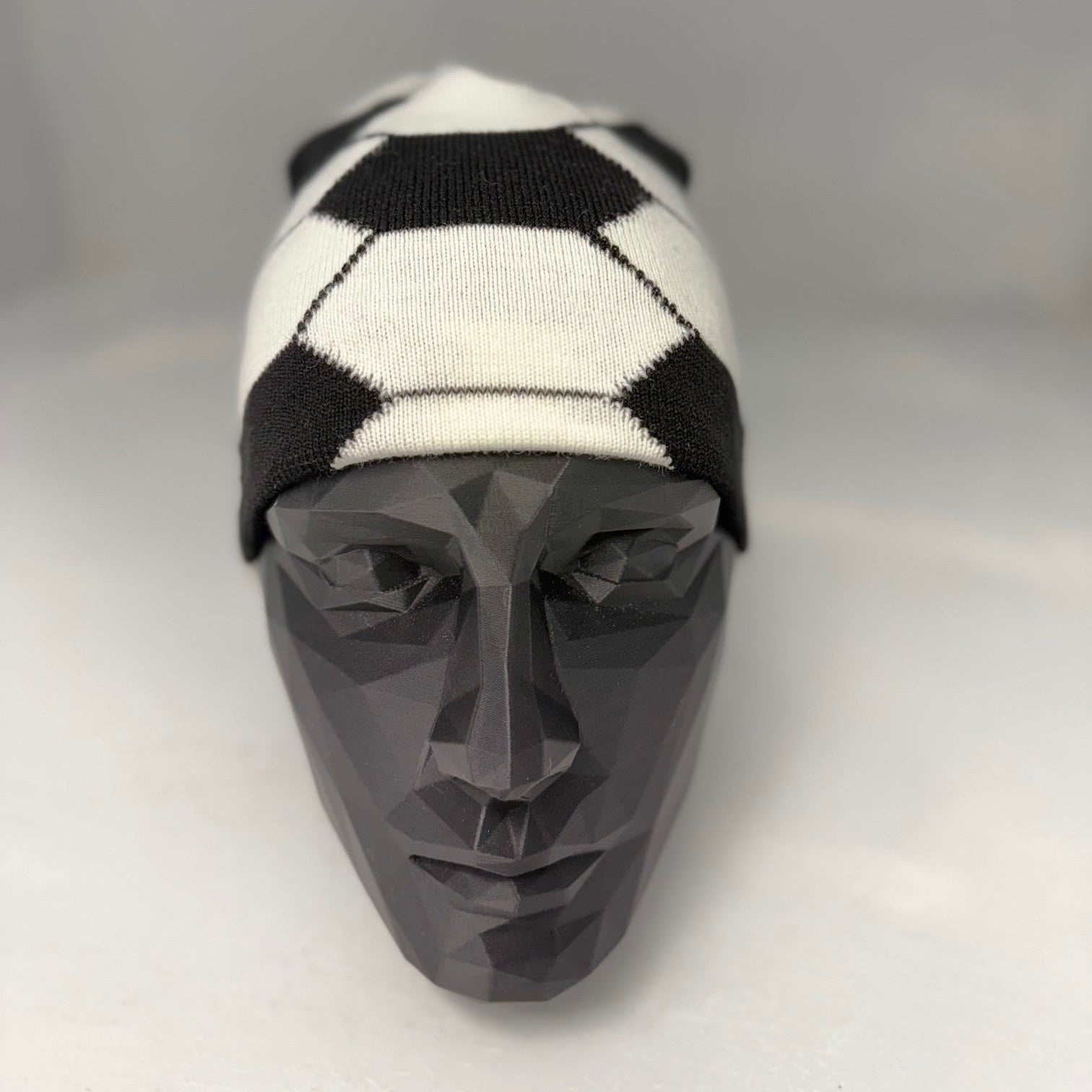 Black and white checkered beanie on a mannequin head against a gray background