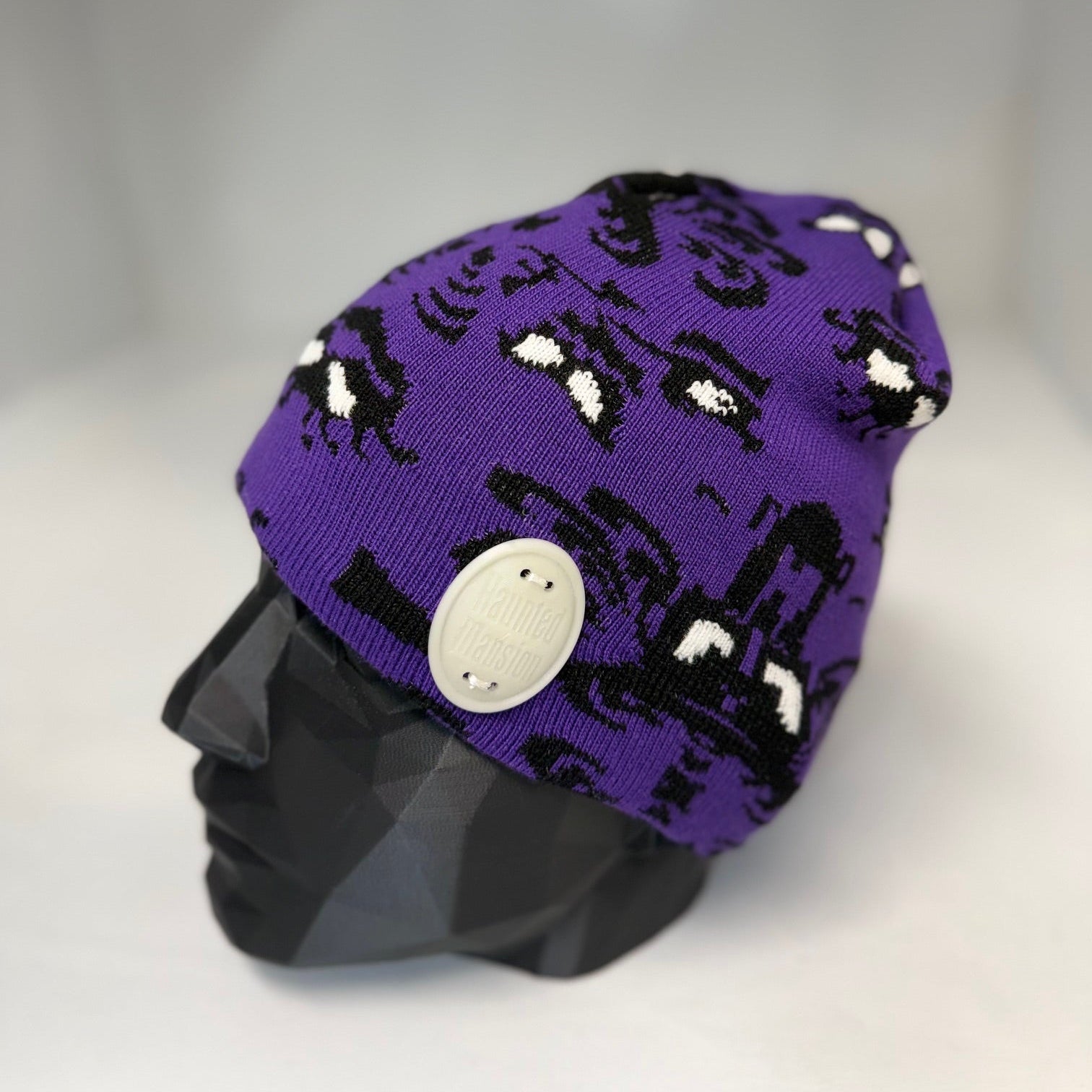 Purple beanie with black and white pattern on a mannequin head against a gray background