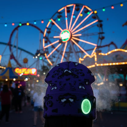 Purple beanie with black patterns and a green patch on a light gray background