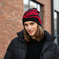 Person wearing a black and red patterned beanie in front of a brick building