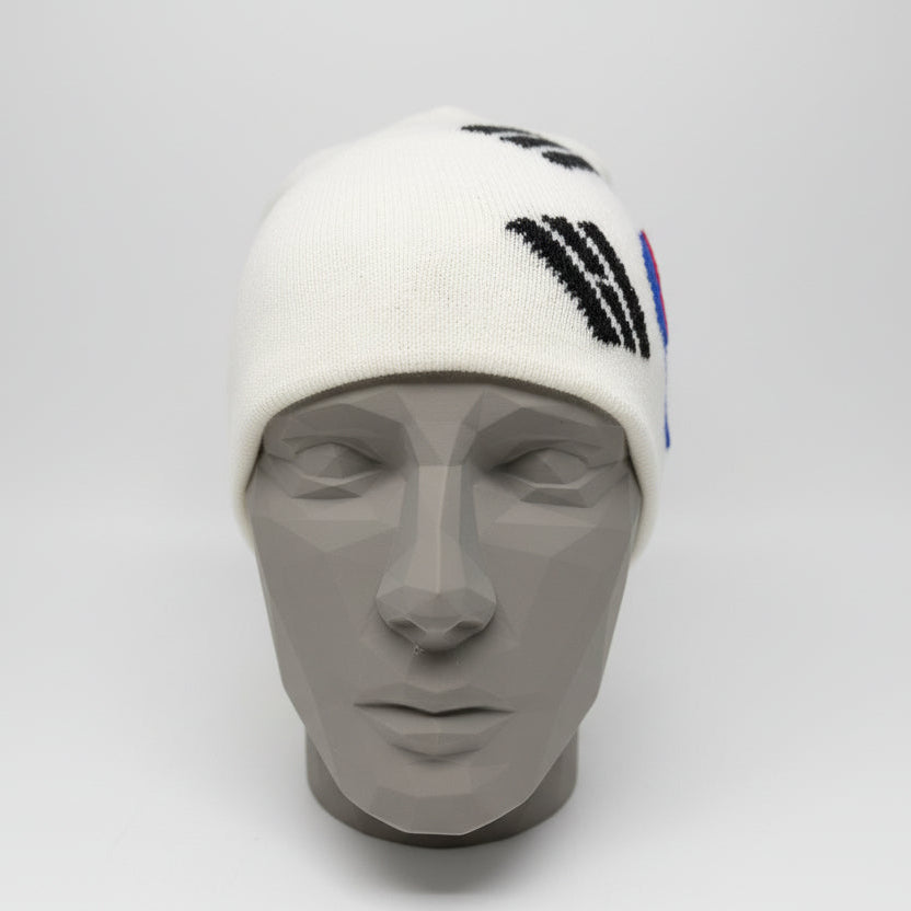 White beanie with black and blue designs on a black mannequin head against a gray background