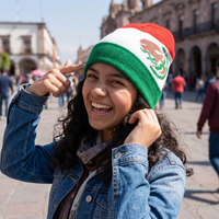 Person wearing a Mexican flag beanie in an outdoor setting with buildings and people in the background