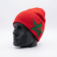 Red beanie with green star design on a black mannequin head against a white background