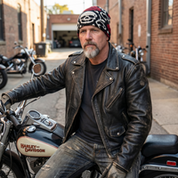Man in leather jacket and beanie sitting on a Harley Davidson motorcycle in an urban setting.