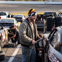 Man with wrench in racing pits wearing pit lane beanie