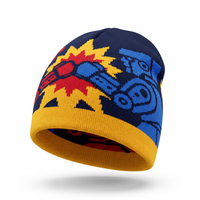 A multicolor knit beanie hat featuring a navy blue base with a yellow and red starburst pattern, blue cartoon-style graphics, and a yellow ribbed cuff, shown on a white background with a soft shadow.