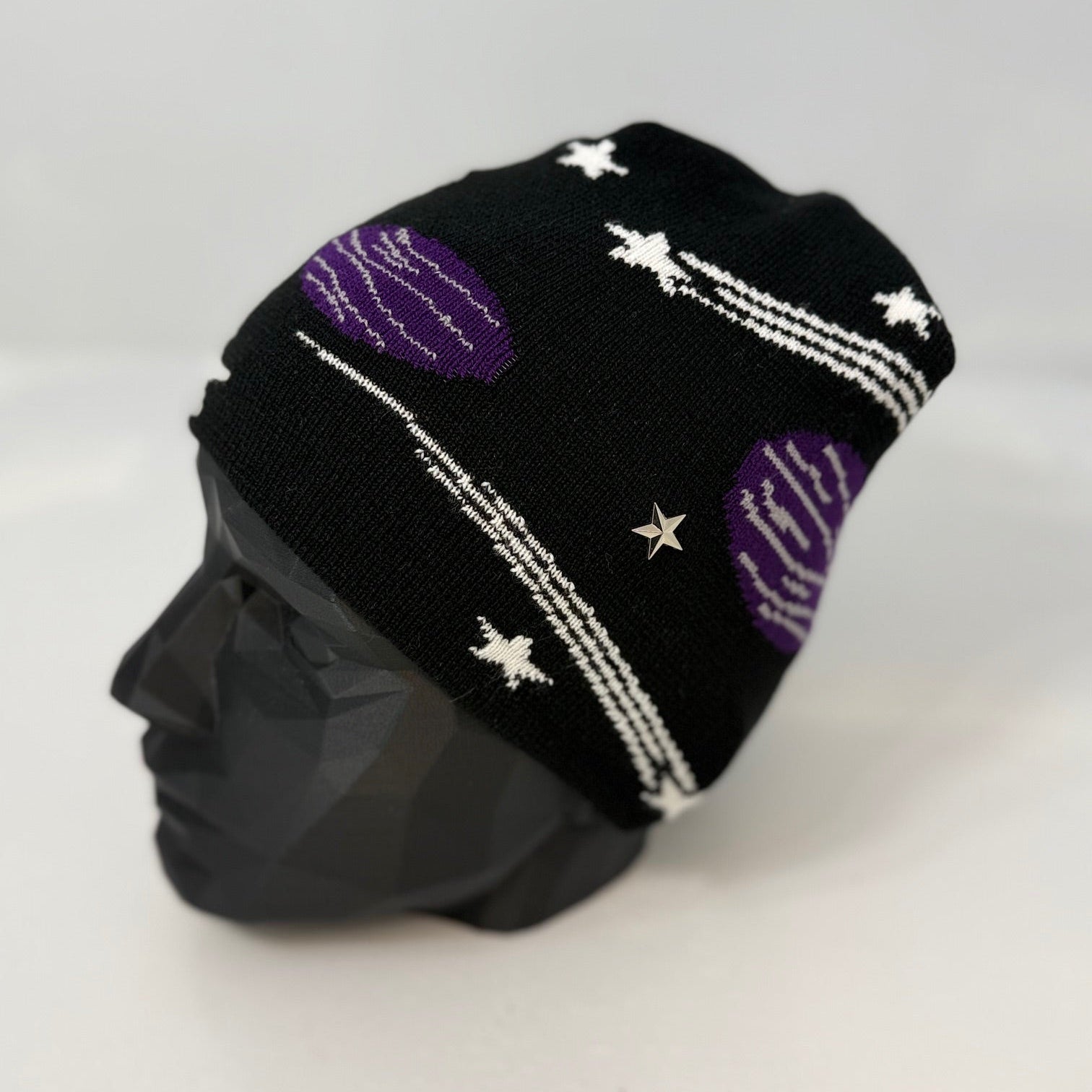 Black knit beanie with purple and white patterns on a mannequin head against a white background