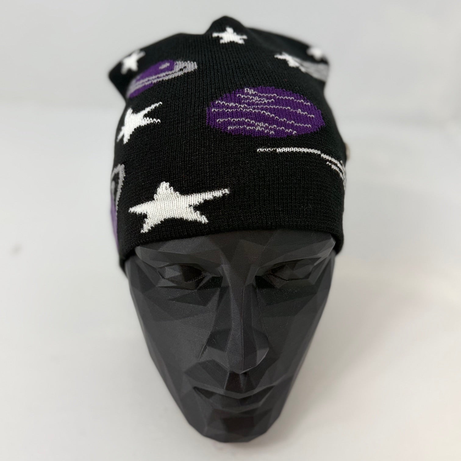 Black beanie with star and planet patterns on a mannequin head against a white background