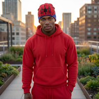 Person wearing a red Spider-Man beanie and hoodie on a rooftop with cityscape background