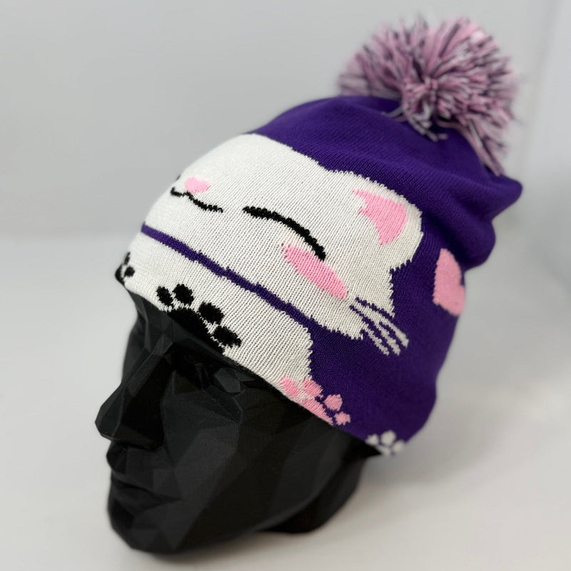 Purple knit beanie with a cat design on a mannequin head against a gray background
