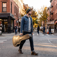 Man carrying guitar case wearing beanie