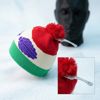 Colorful knit hat with a fork through the pom-pom on a light blue background