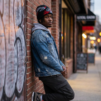 Man leaning against a brick wall with graffiti in an urban setting