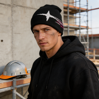 Man wearing a black beanie and hoodie standing in front of scaffolding.