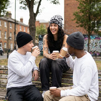 Three people sitting on a bench outdoors, drinking coffee.