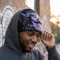 Person wearing a dark hoodie and a patterned beanie outdoors