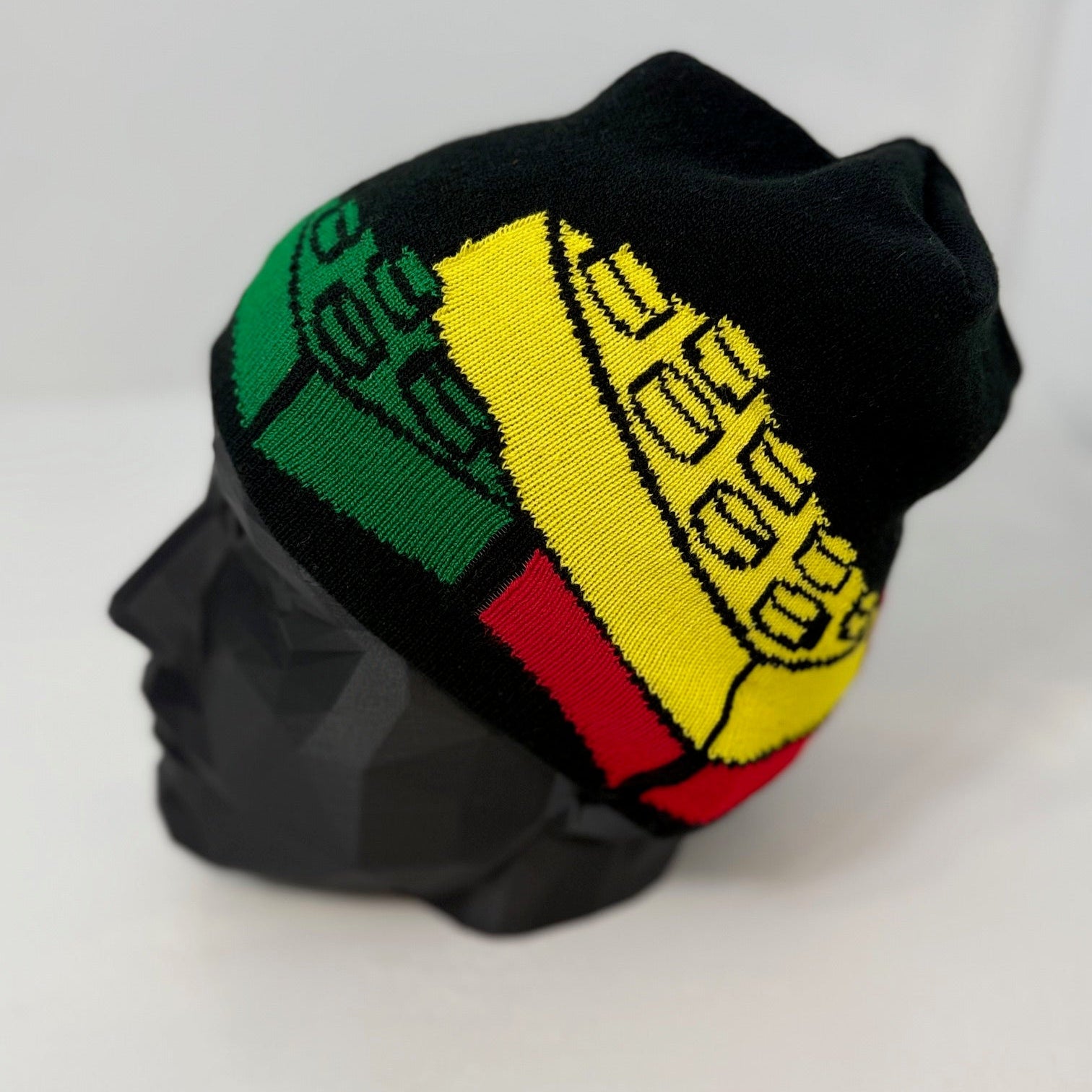 Black beanie with green, yellow, and red pattern on a mannequin head against a white background